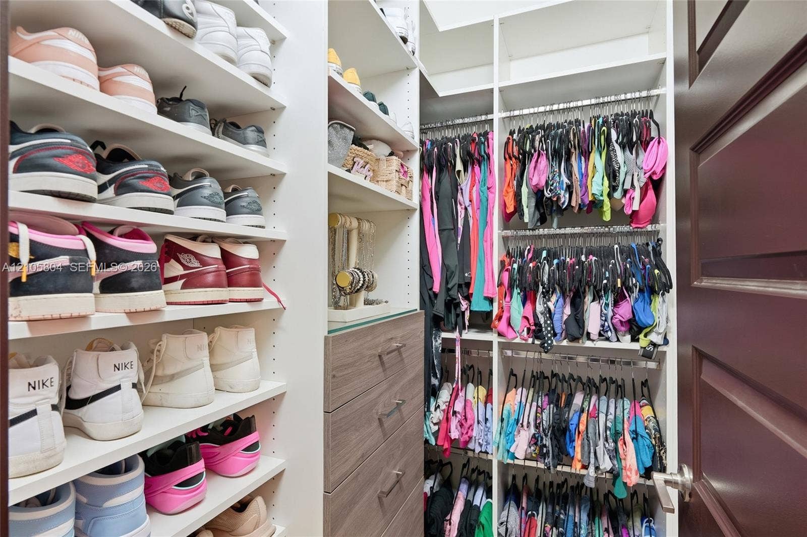 15932 SW 136th Way, Miami, FL 33196 Custom walk-in closet featuring extensive built-in white shelving, integrated wood-finish cabinetry with drawers, and multi-tier hanging rods