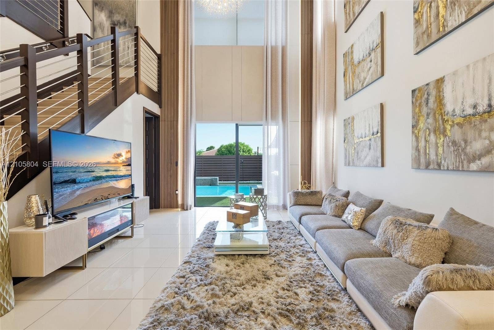 15932 SW 136th Way, Miami, FL 33196 Double-height ceiling, polished tile flooring, staircase featuring dark wood-finish railings with horizontal cable balusters, and floor-to-ceiling glass sliding doors