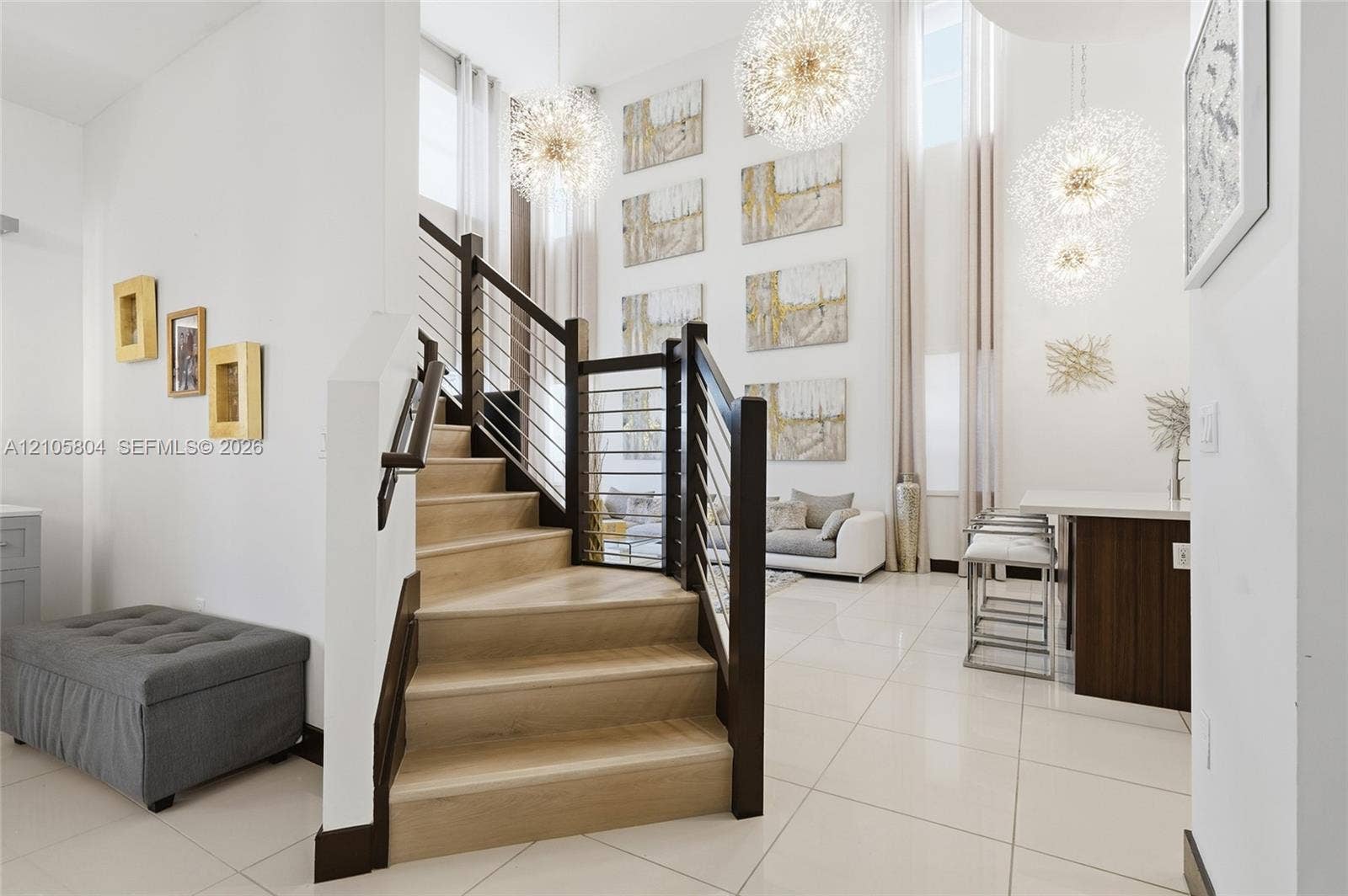 15932 SW 136th Way, Miami, FL 33196 Staircase featuring wood-finish treads, dark wood posts, and a cable railing system, complemented by high-gloss floor tile and suspended globe-style pendant light fixtures