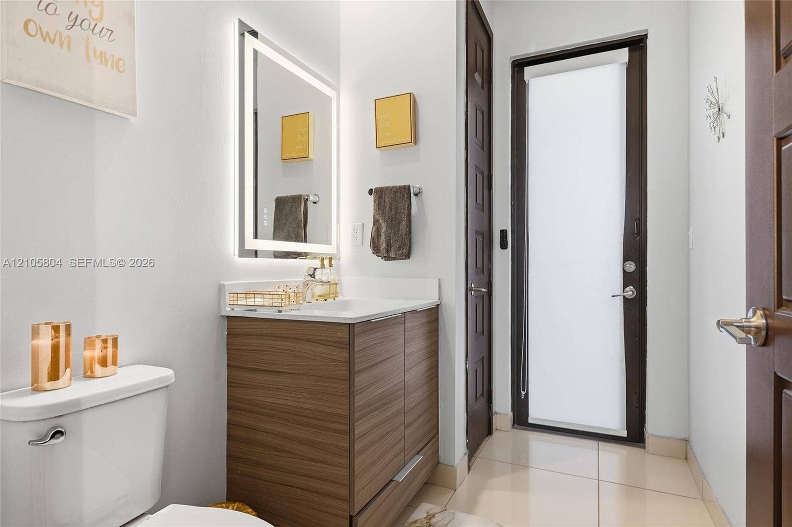 15932 SW 136th Way, Miami, FL 33196 Wood-finish cabinetry, rectangular under-mount sink, integrated LED-backlit mirror, and polished stone-finish countertop