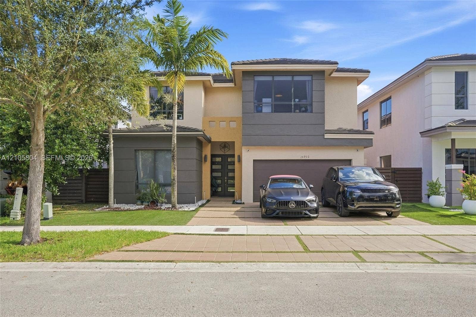 15932 SW 136th Way, Miami, FL 33196 Two-story contemporary exterior featuring a concrete paver driveway, multi-toned stucco finish, large-format picture windows, and double-entry glass doors