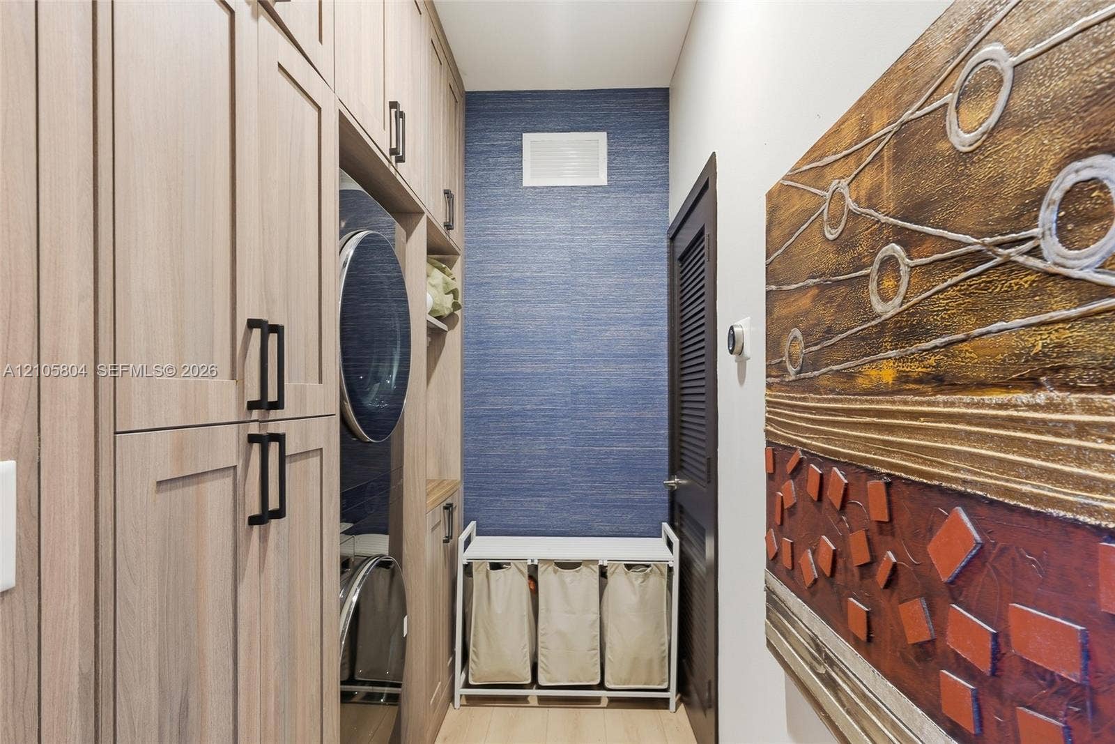 15932 SW 136th Way, Miami, FL 33196 Custom floor-to-ceiling cabinetry with matte black hardware, integrated laundry appliances, and textured blue accent wall