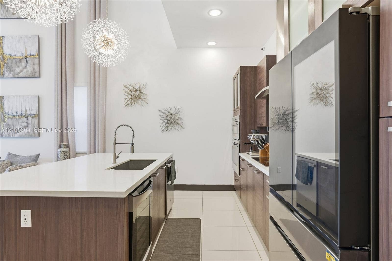 15932 SW 136th Way, Miami, FL 33196 Kitchen featuring a waterfall-edge island with a quartz countertop, flat-panel cabinetry, high-ceiling drum pendant lighting, and stainless steel built-in appliances