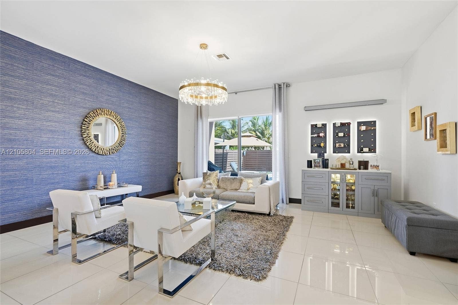 15932 SW 136th Way, Miami, FL 33196 Textured blue accent wall, large-format tile flooring, drum-style crystal chandelier, and built-in cabinetry featuring integrated backlit shelving