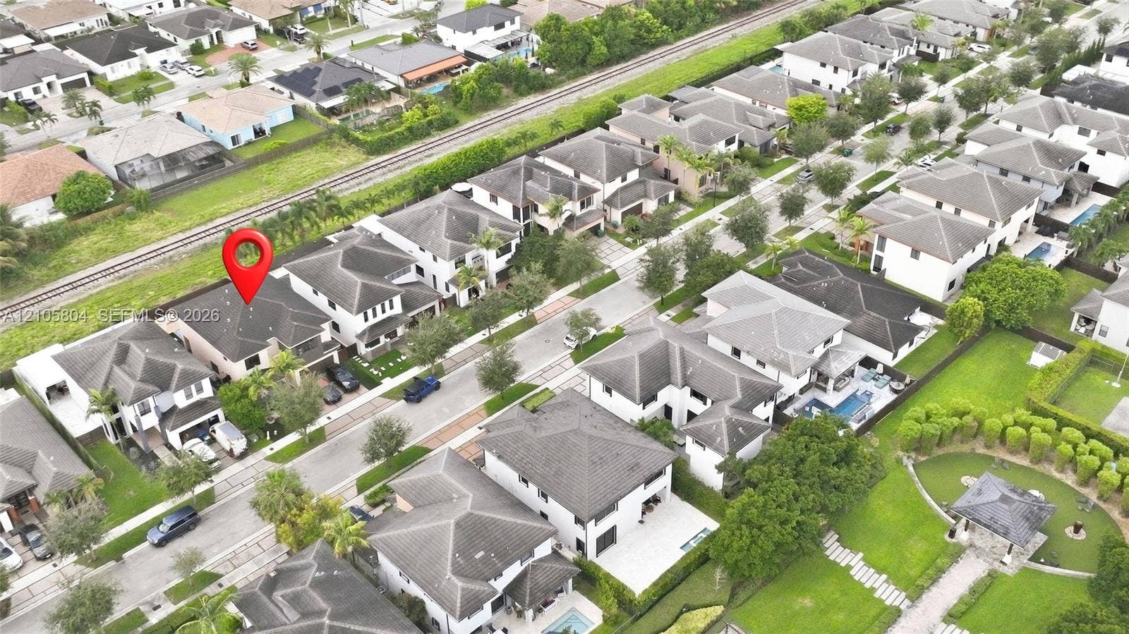 15932 SW 136th Way, Miami, FL 33196 Aerial perspective of a multi-story residence featuring a hipped roof, attached garage, paved driveway, and manicured landscaping
