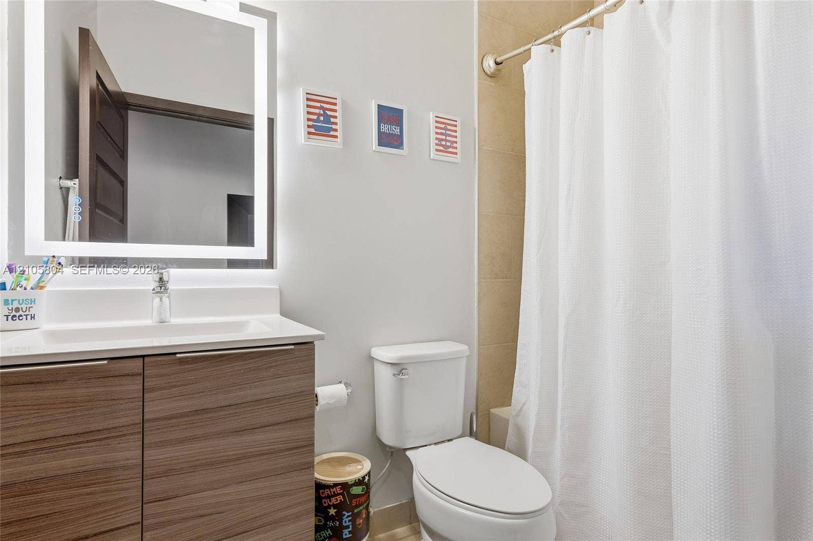 15932 SW 136th Way, Miami, FL 33196 Bathroom vanity featuring a wood-finish cabinet, integrated countertop, and LED-backlit mirror