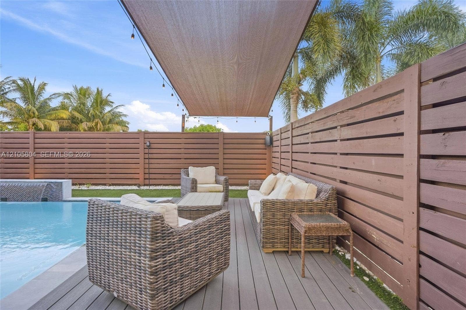 15932 SW 136th Way, Miami, FL 33196 Swimming pool with water feature, composite decking, horizontal wood privacy fencing, and an overhead fabric shade canopy