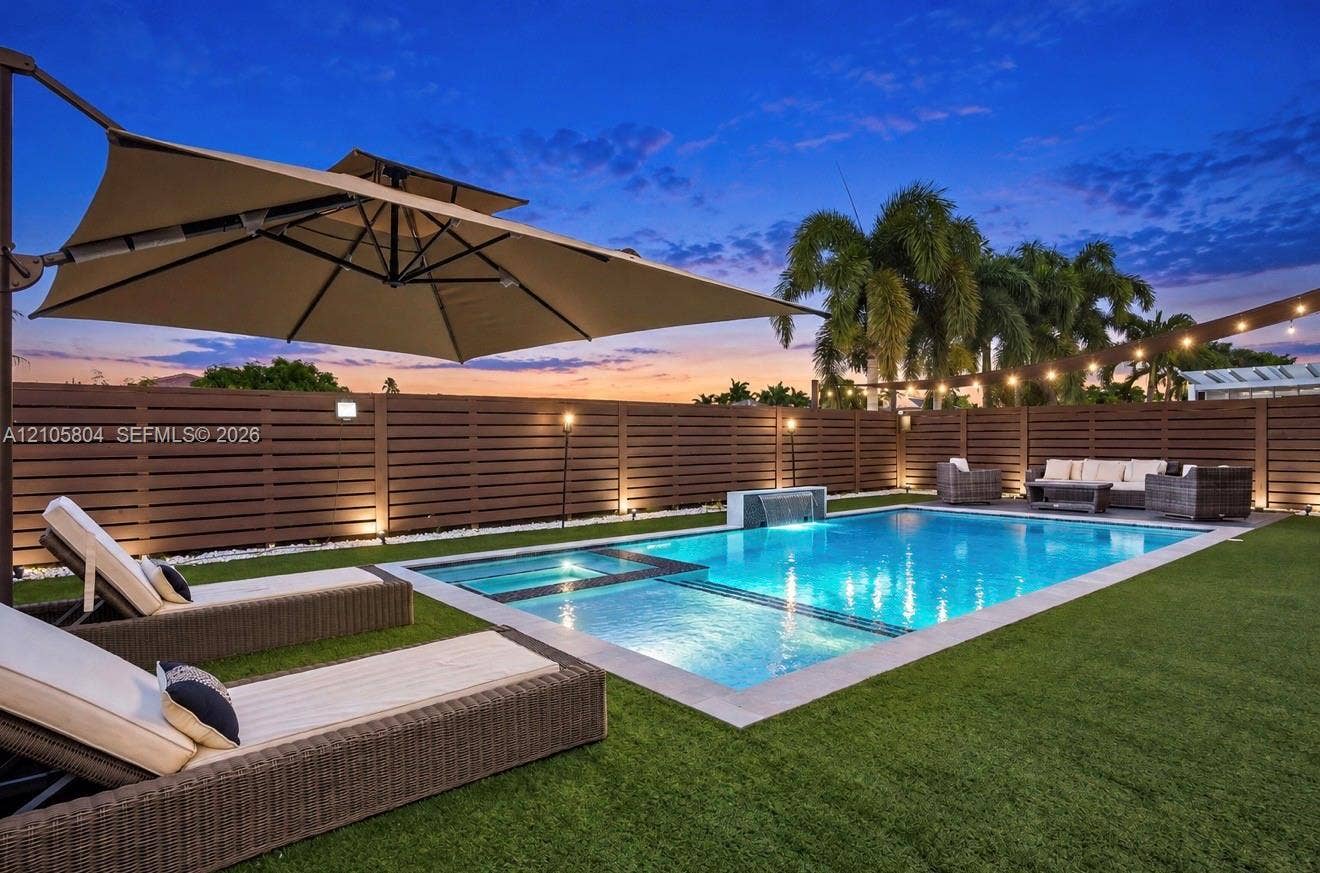 15932 SW 136th Way, Miami, FL 33196 Backyard oasis featuring a swimming pool with integrated spa and water feature, surrounding synthetic turf, and perimeter horizontal privacy fencing