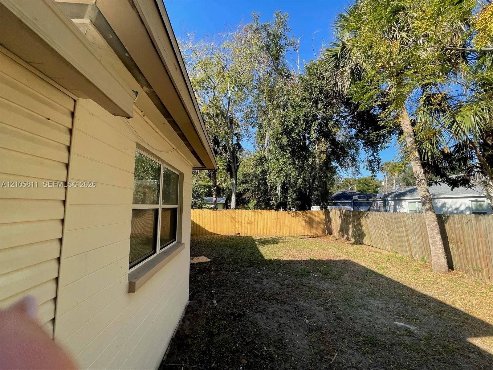 Exterior siding with multi-pane windows and a wood-slat privacy fence enclosing the rear grounds
