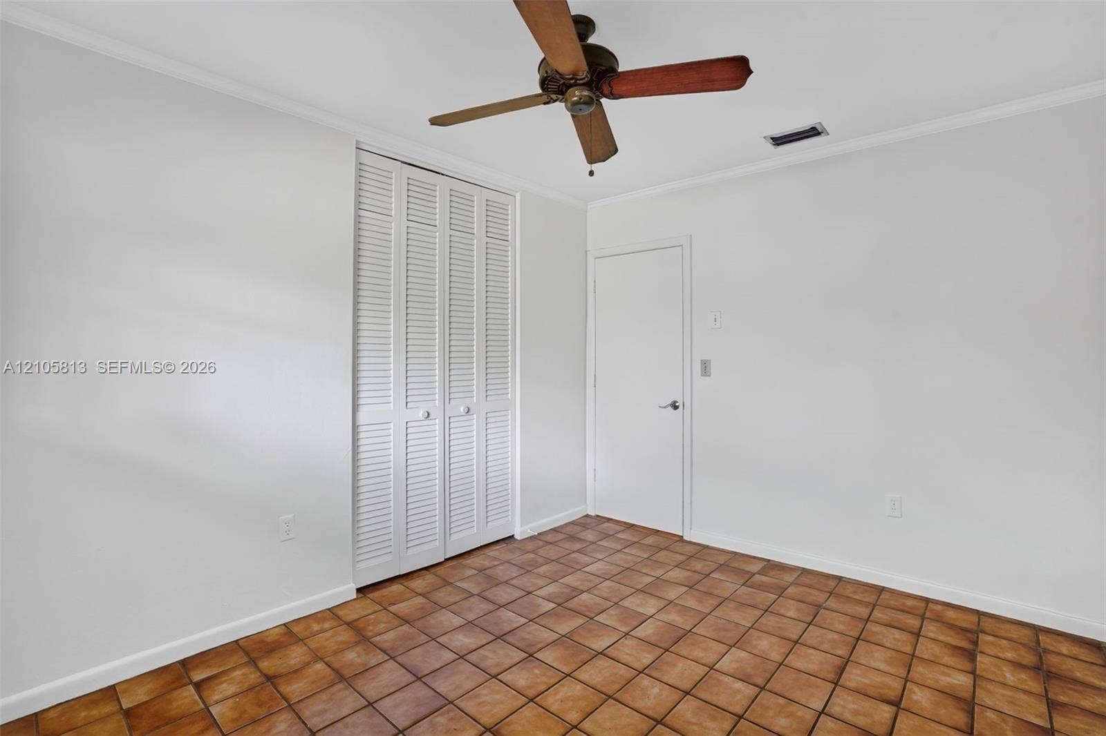 Interior room featuring tile flooring, louvered closet doors, and a ceiling fan