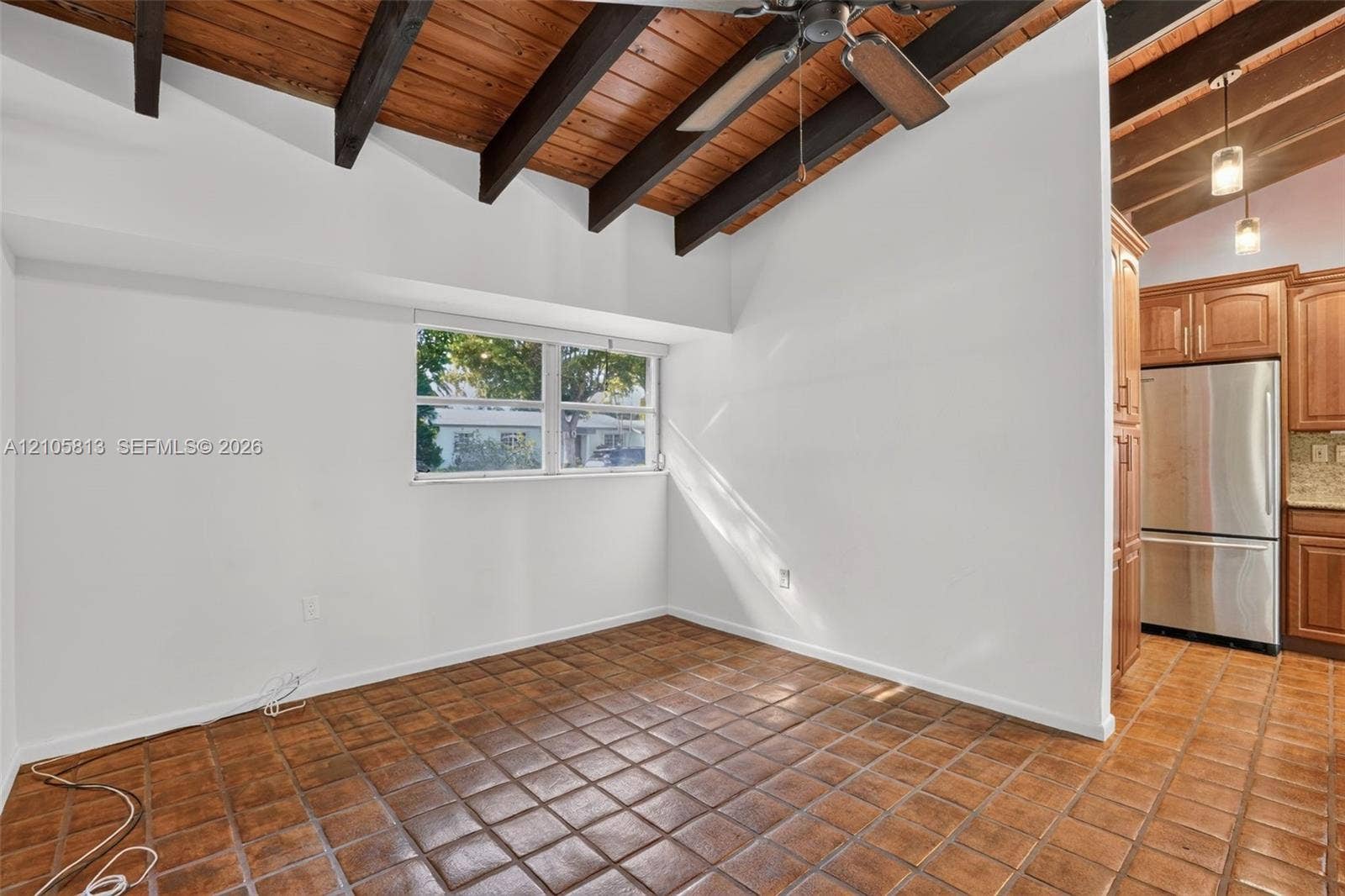Vaulted ceilings featuring exposed wood beams, tile flooring, and built-in stainless steel appliances