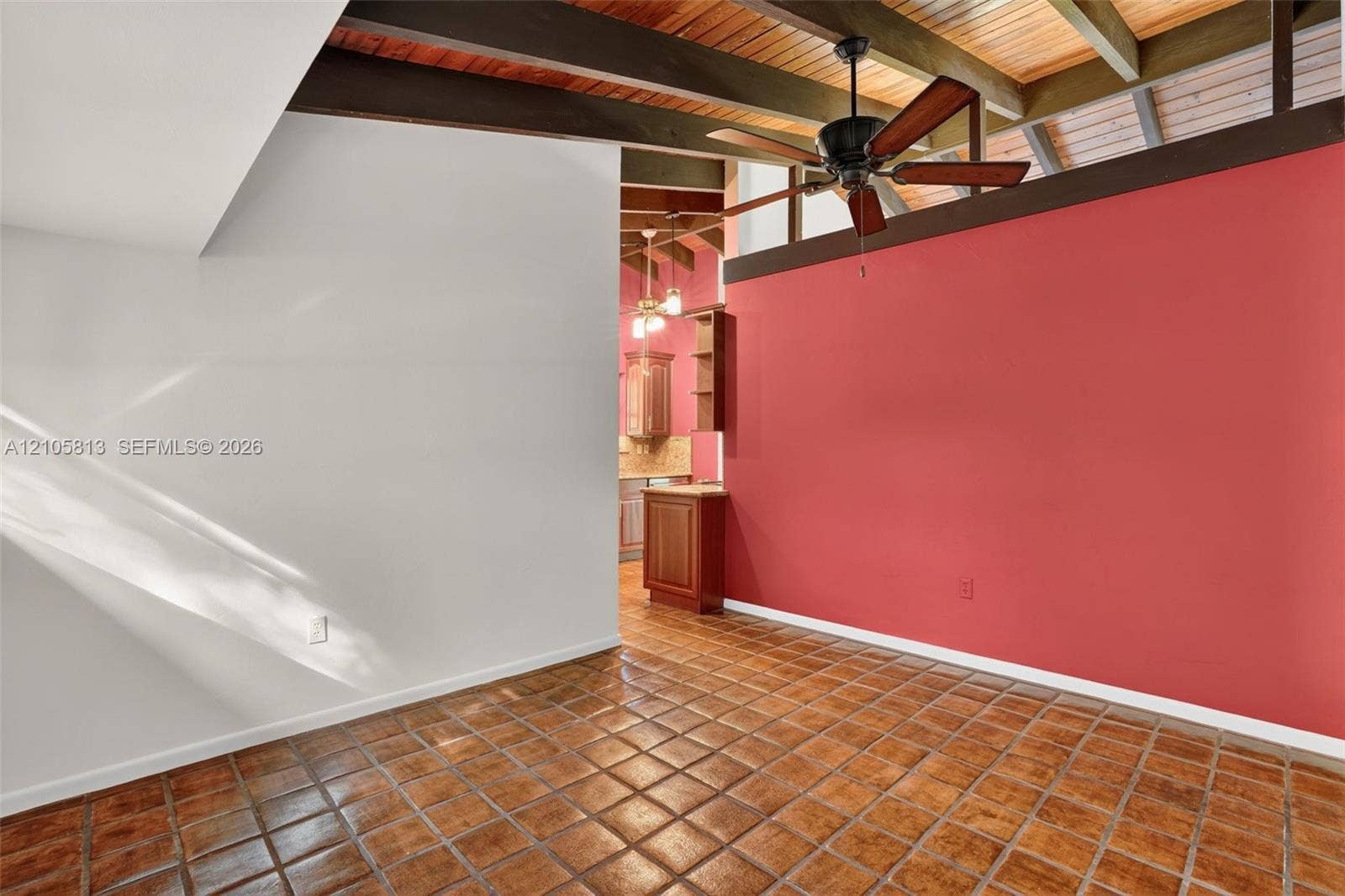 Exposed wood ceiling beams, vaulted ceiling, ceramic tile flooring, and a ceiling fan