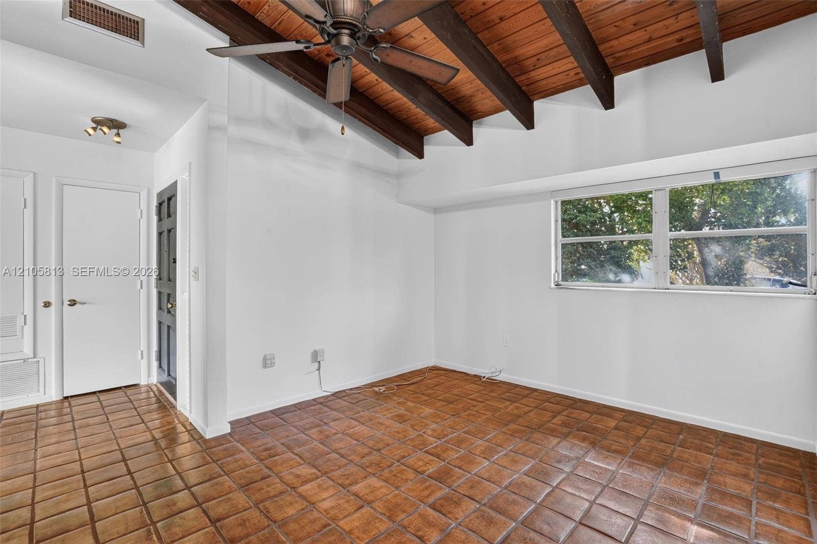 Vaulted ceiling featuring exposed wood beams and wood planking, tile flooring, and a ceiling fan