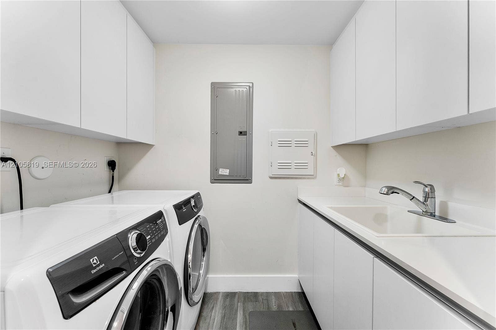 1180 N Federal Highway, #810, Fort Lauderdale, FL 33304 Laundry area featuring white cabinetry, integrated sink with chrome faucet, and wood-finish flooring