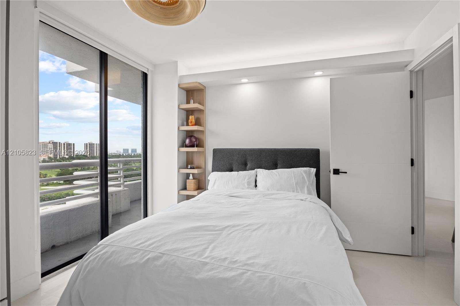 Floor-to-ceiling sliding glass door, recessed lighting, built-in recessed shelving, neutral tile flooring, and access to a private balcony