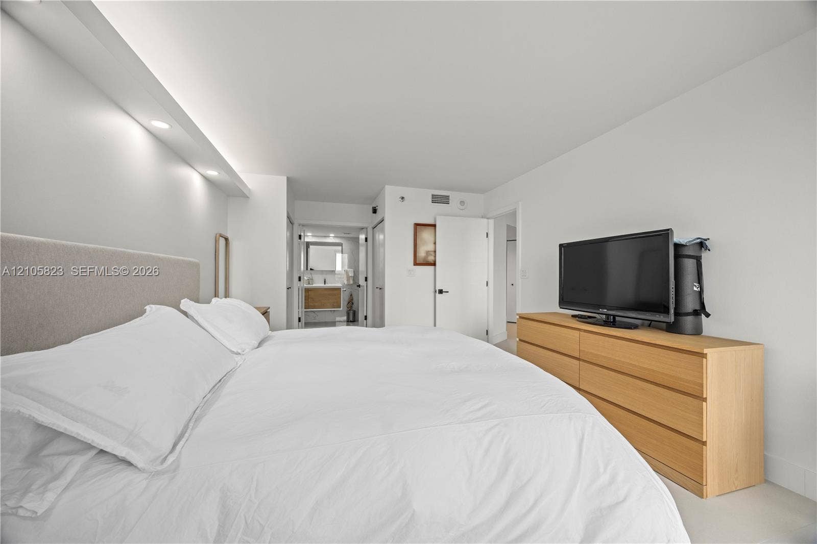 Bedroom featuring a recessed ceiling soffit with integrated downlighting, smooth-finish ceilings, and solid-core interior doors