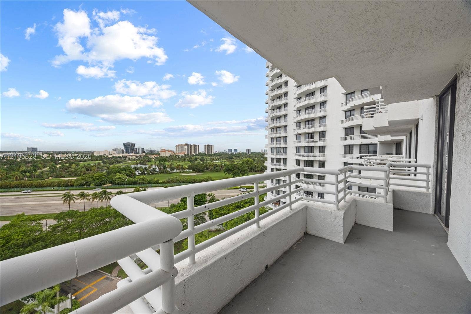 Covered concrete balcony featuring white metal railings