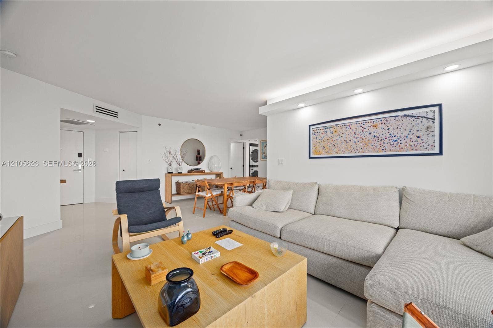 Open-concept living space featuring high-gloss tile flooring, recessed cove lighting, and smooth-finish walls