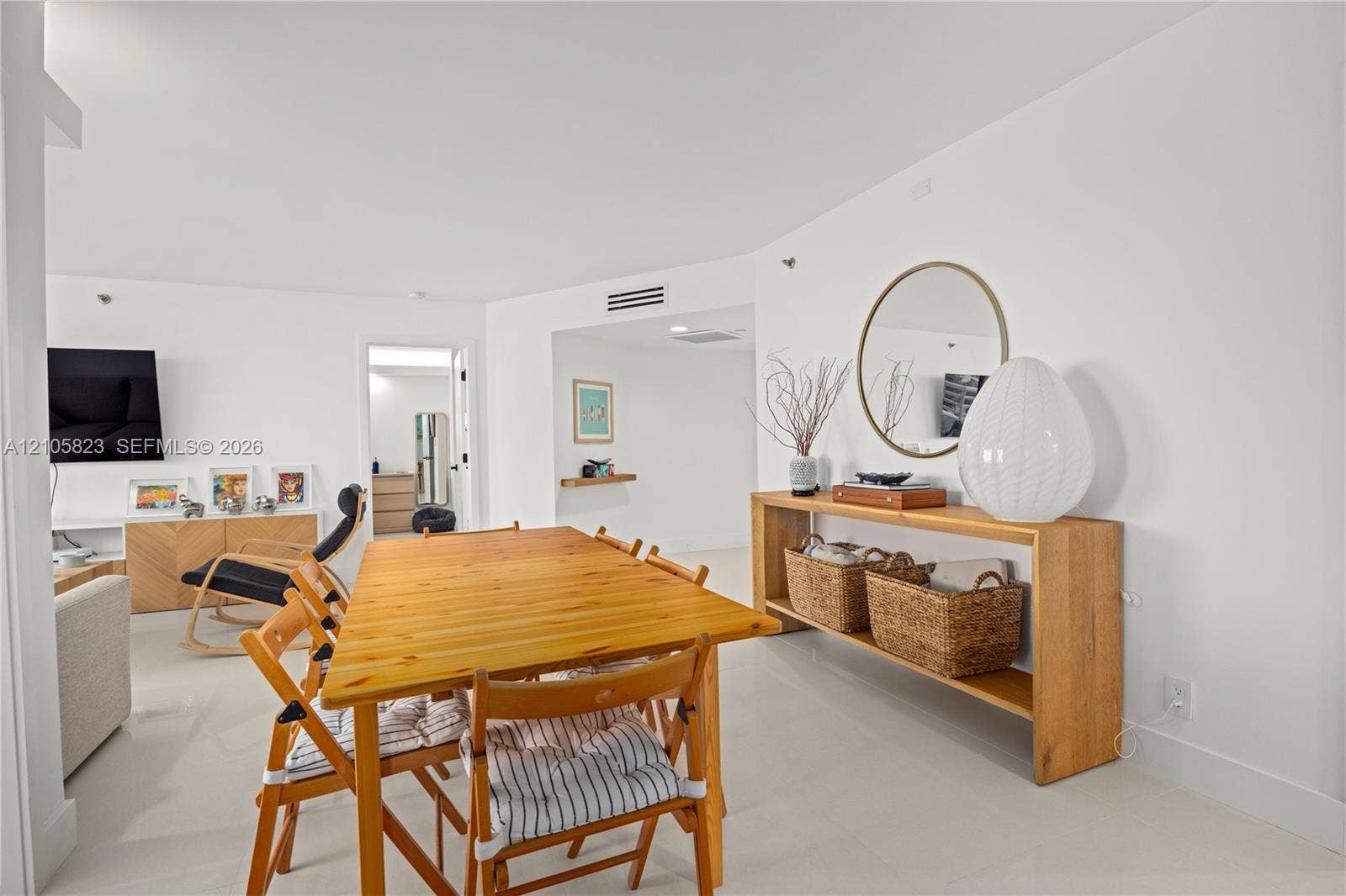 Open-concept interior featuring smooth white wall surfaces, polished tile flooring, and a floating wood-finish wall shelf