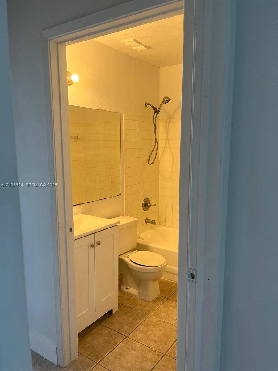 11233 W Atlantic Boulevard, #207, Coral Springs, Coral Springs, FL 33071 Bathroom featuring tile flooring, a white vanity cabinet, a wall-mounted mirror, a tub-shower combination with white subway-style wall tiling, and a handheld shower head
