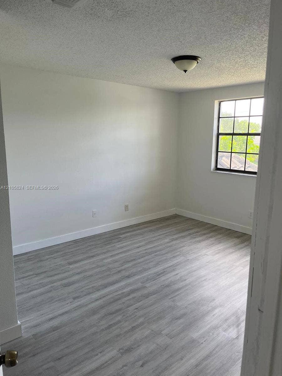 11233 W Atlantic Boulevard, #207, Coral Springs, Coral Springs, FL 33071 Interior space featuring wood-finish flooring, a multi-pane window, and a dome-style flush mount ceiling light