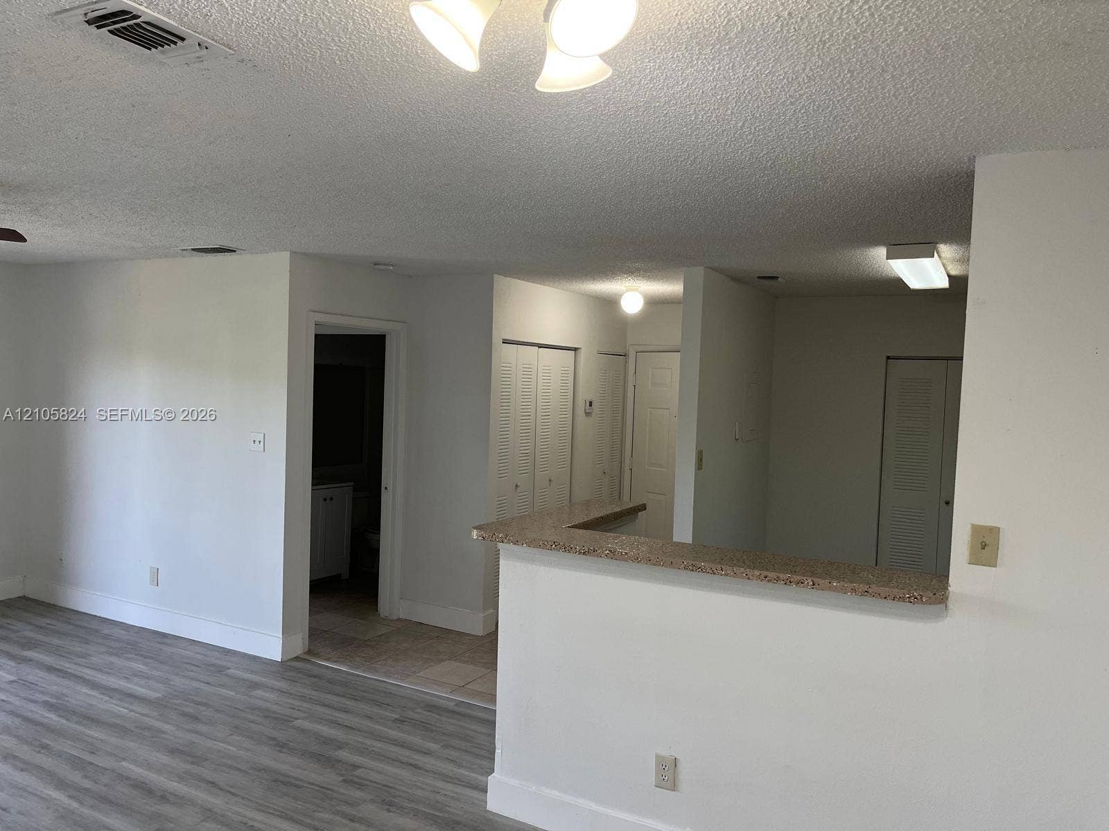 11233 W Atlantic Boulevard, #207, Coral Springs, Coral Springs, FL 33071 Interior space featuring wood-finish flooring, a stone-composite breakfast bar, multi-panel louvered closet doors, and neutral wall tones