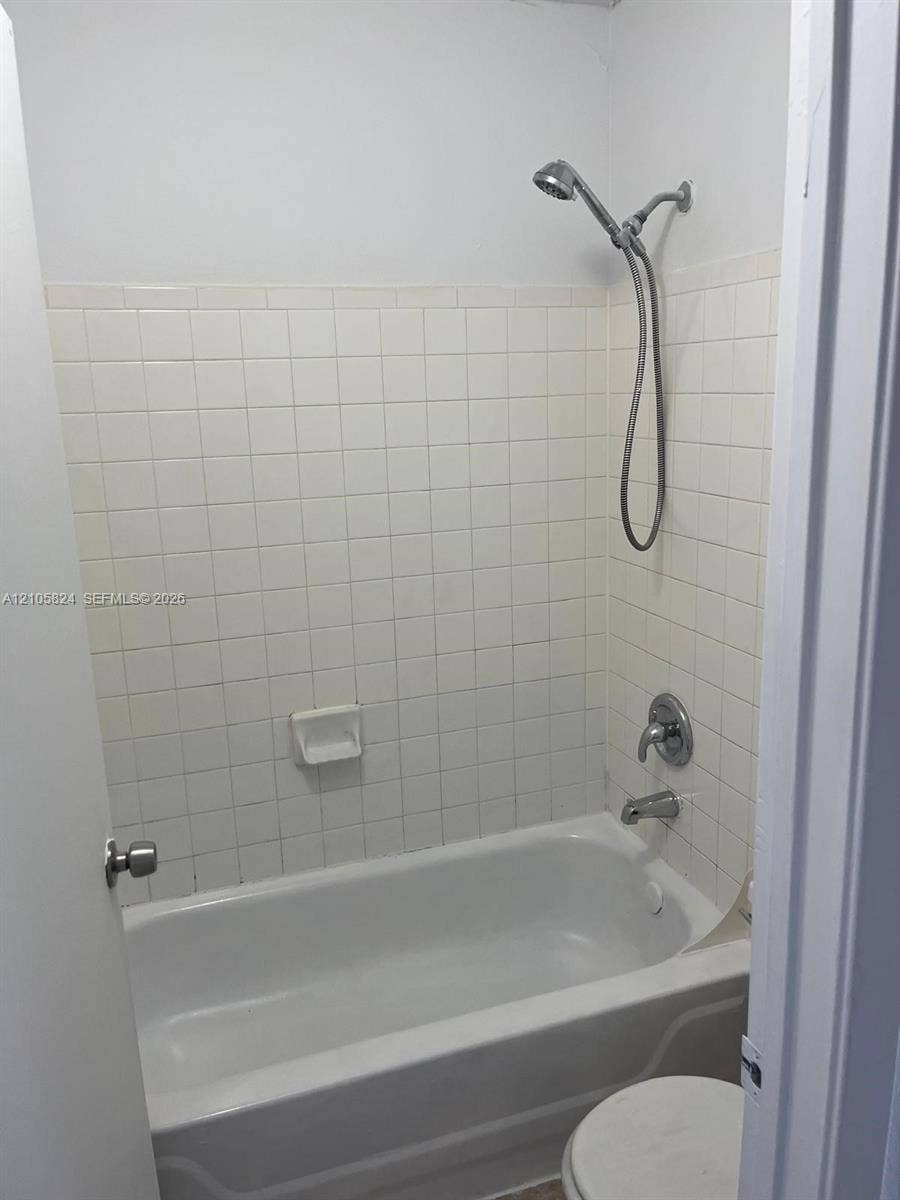 11233 W Atlantic Boulevard, #207, Coral Springs, Coral Springs, FL 33071 Bathtub enclosure featuring white square tile surround, chrome wall-mounted showerhead, and integrated soap dish