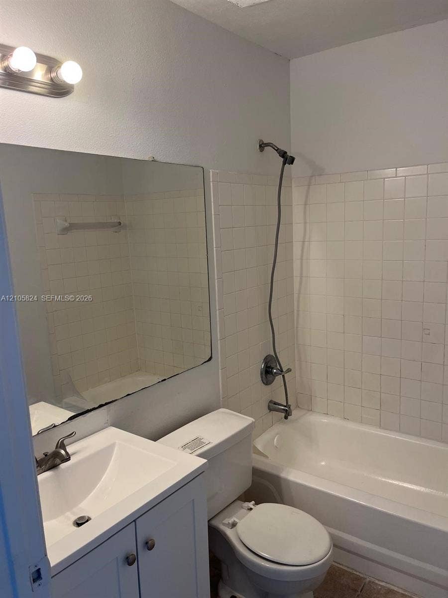 11233 W Atlantic Boulevard, #207, Coral Springs, Coral Springs, FL 33071 Bathroom featuring a white vanity cabinet with an integrated sink, rectangular wall-mounted mirror, two-light fixture, and a tile-surround shower and tub combination