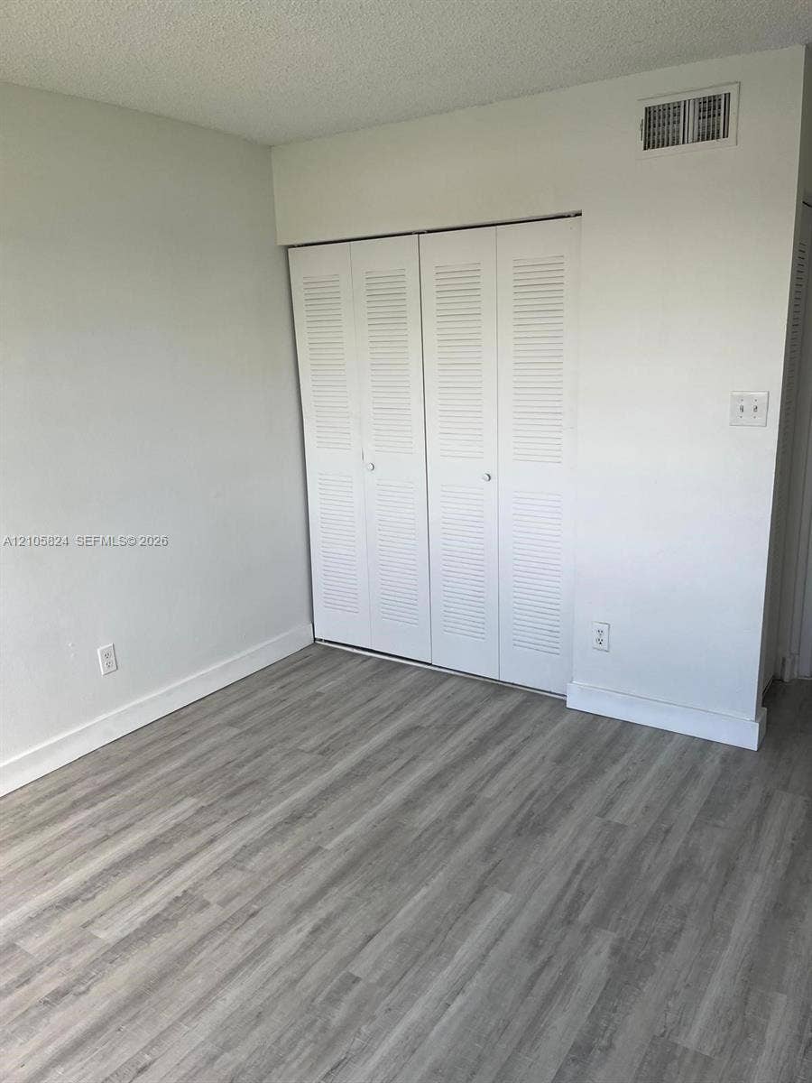 11233 W Atlantic Boulevard, #207, Coral Springs, Coral Springs, FL 33071 Wood-finish flooring paired with white louvered-style closet doors