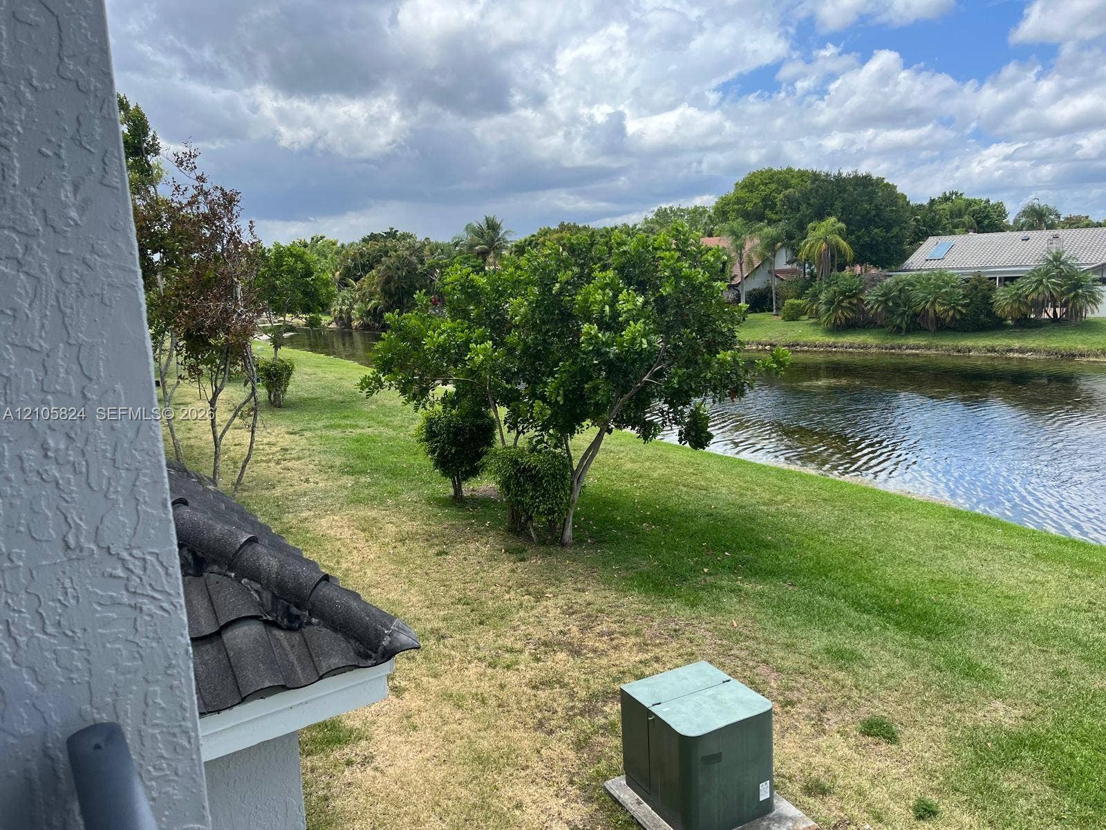 11233 W Atlantic Boulevard, #207, Coral Springs, Coral Springs, FL 33071 Waterfront backyard featuring a grass lawn, mature trees, and concrete tile roofing
