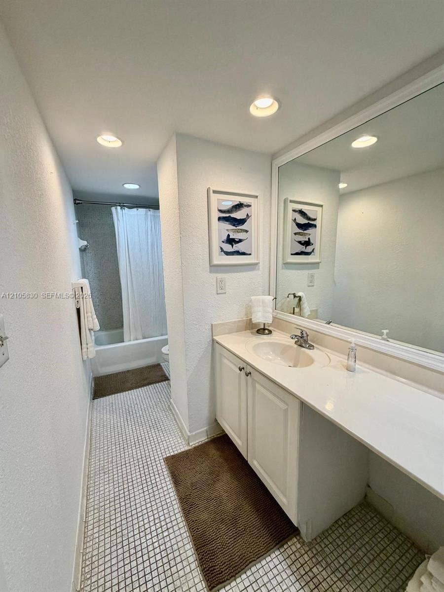 4001 S Ocean Drive, #14F, Hollywood, Hollywood, FL 33019 Vanity featuring white cabinetry, a solid surface countertop with an integrated basin, a polished chrome faucet, and a large wall-mounted mirror with a white frame, accompanied by recessed lighting and tiled flooring