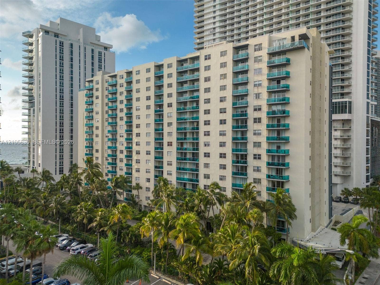 4001 S Ocean Drive, #14F, Hollywood, Hollywood, FL 33019 High-rise residential building featuring stacked balconies with glass railings and mature tropical landscaping