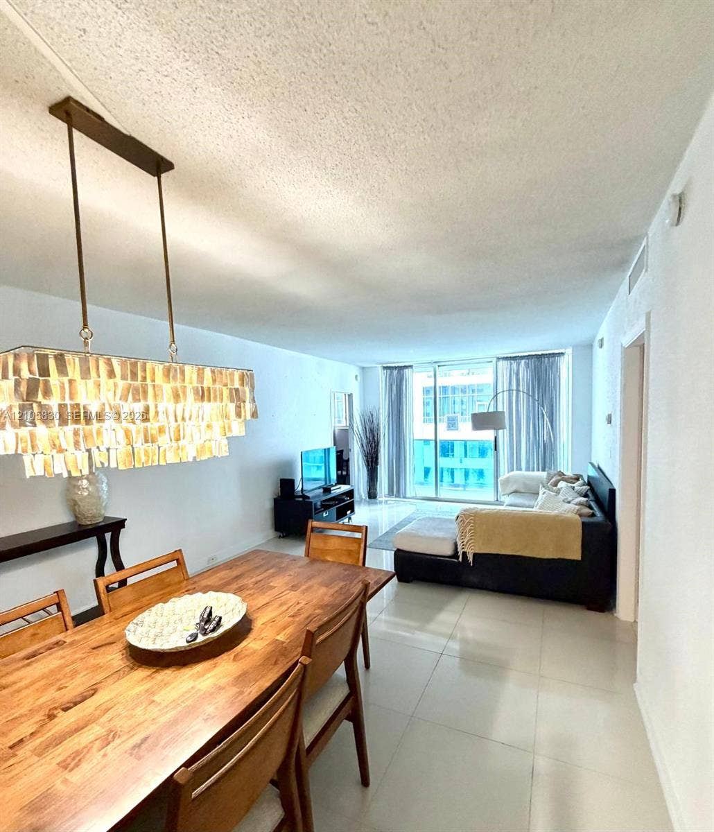 4001 S Ocean Drive, #14F, Hollywood, Hollywood, FL 33019 Rectangular light fixture with metallic pendant detailing, large-format tile flooring, and floor-to-ceiling glass sliding doors leading to an exterior balcony