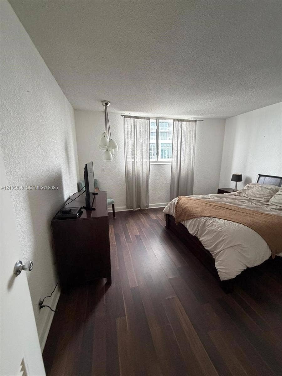4001 S Ocean Drive, #14F, Hollywood, Hollywood, FL 33019 Wood-finish flooring, multi-globe pendant lighting, and a window with neutral-toned treatments