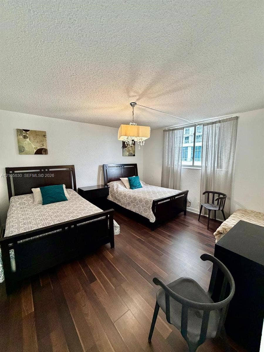 4001 S Ocean Drive, #14F, Hollywood, Hollywood, FL 33019 Wood-finish flooring, textured ceiling, and a multi-tiered crystal-style chandelier with a fabric shade