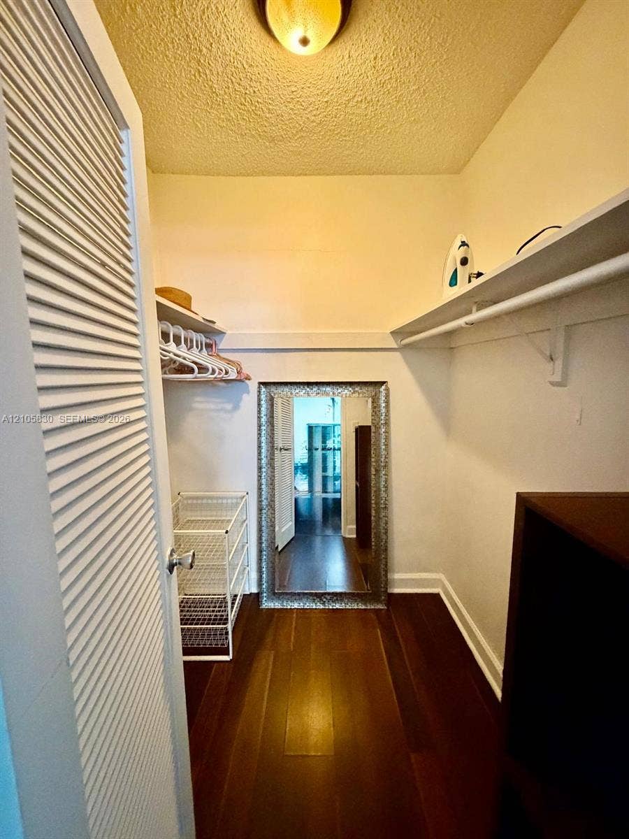 4001 S Ocean Drive, #14F, Hollywood, Hollywood, FL 33019 Storage space featuring louvered bi-fold doors, wood-finish flooring, and built-in upper shelving with integrated hanging rods