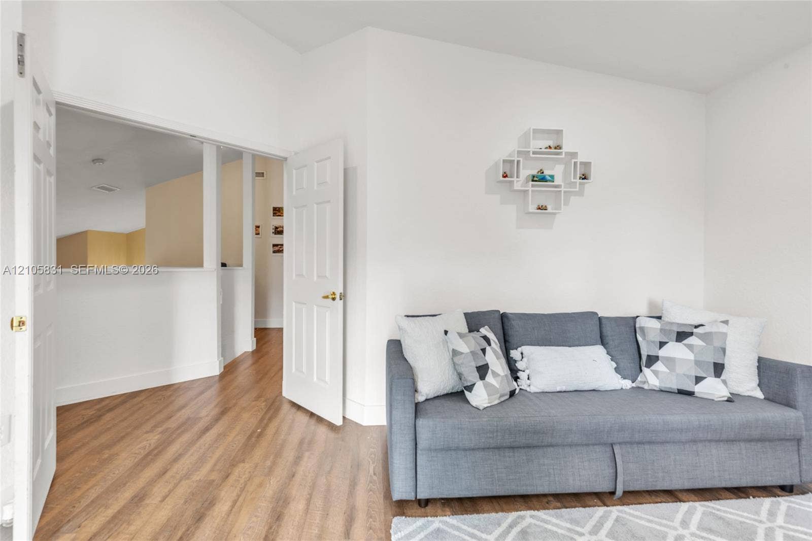 15612 SW 16th Court, Pembroke Pines, FL 33027 Room featuring wood-finish flooring, a six-panel interior door with brass hardware, and a built-in wall niche