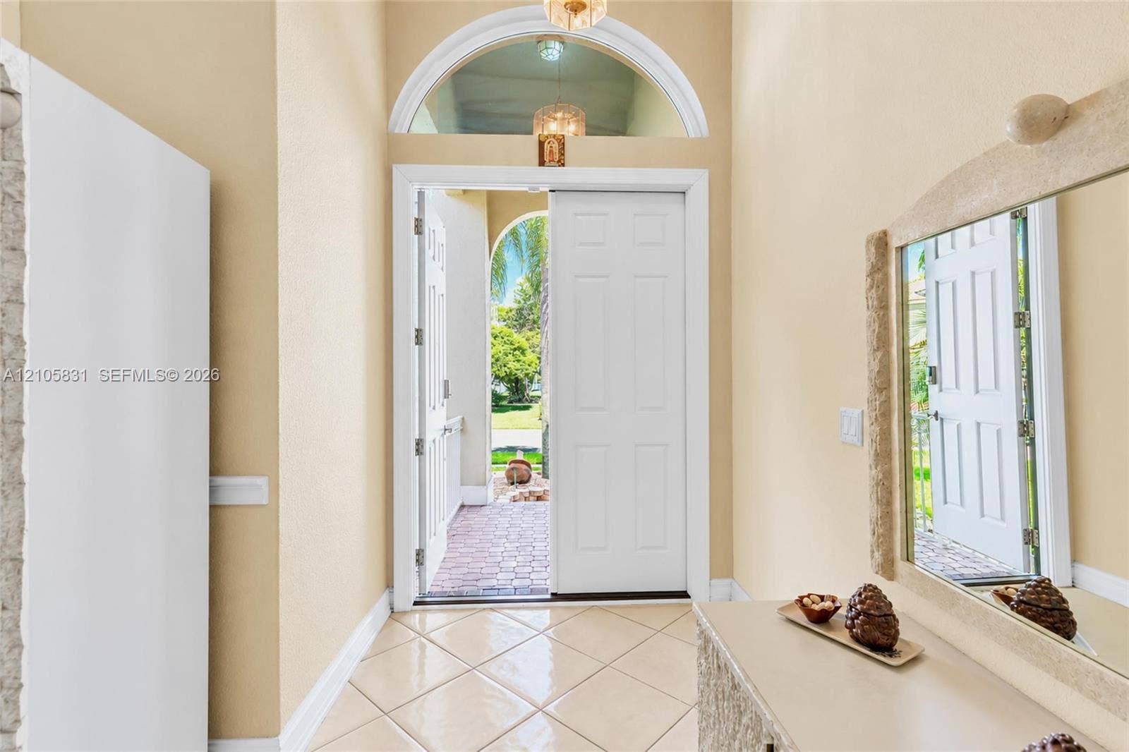 15612 SW 16th Court, Pembroke Pines, FL 33027 Entryway featuring an arched transom window, a six-panel door, high ceilings, and neutral tile flooring