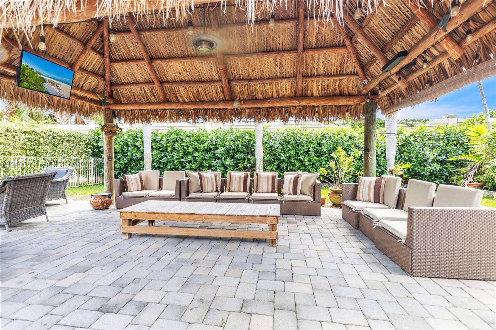 15612 SW 16th Court, Pembroke Pines, FL 33027 Outdoor pavilion featuring a thatched roof, exposed timber beams, integrated ceiling fan, and stone paver patio