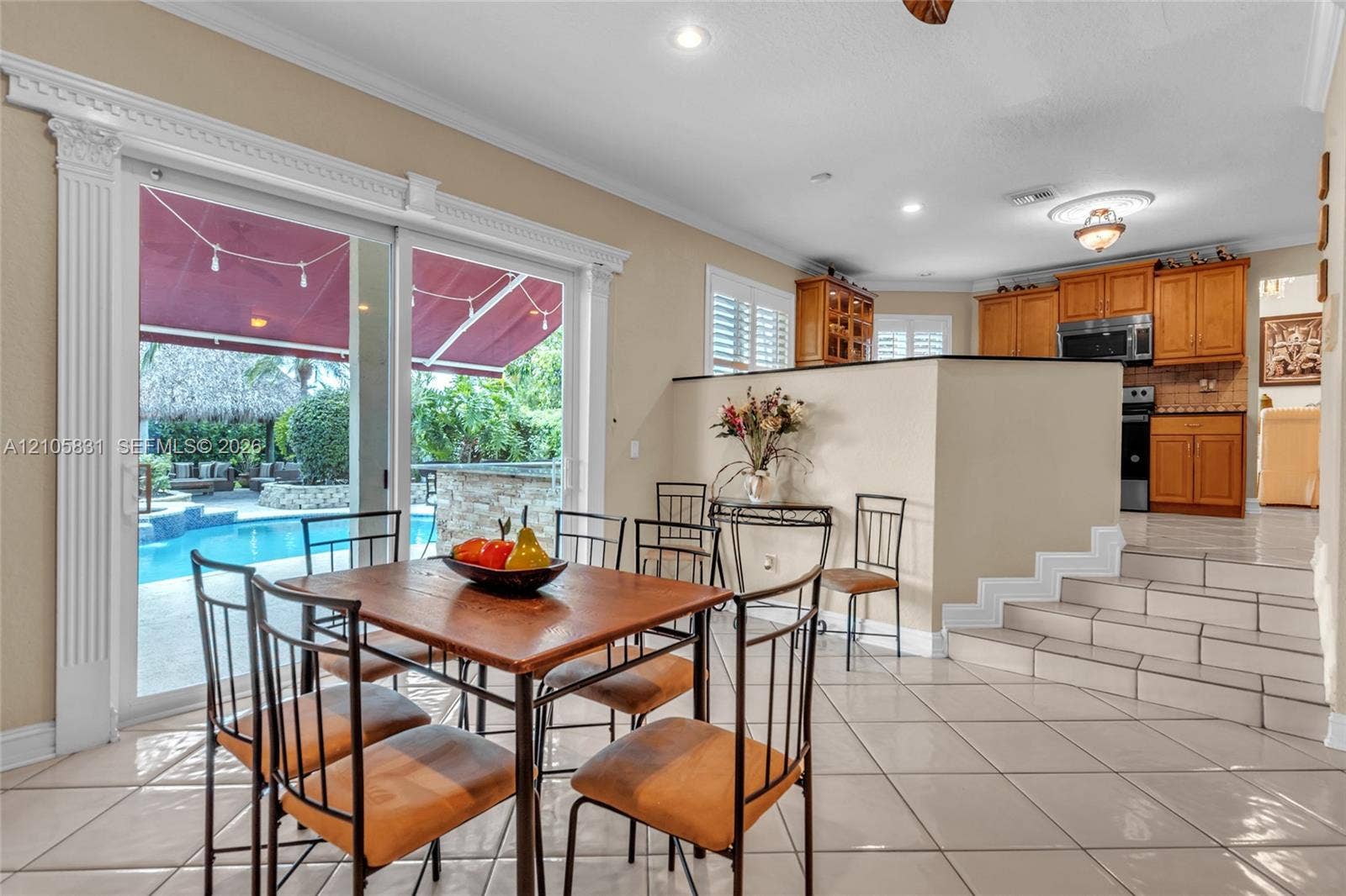 15612 SW 16th Court, Pembroke Pines, FL 33027 Sliding glass doors with decorative pilaster molding, ceramic tile flooring, tiered multi-level interior, and light-tone wood cabinetry