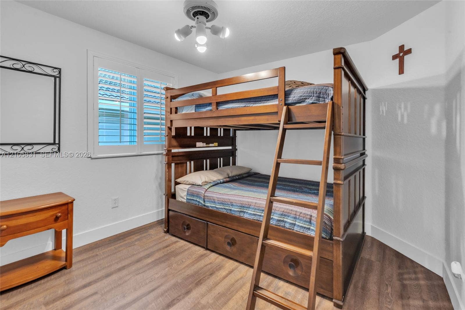 15612 SW 16th Court, Pembroke Pines, FL 33027 Bedroom featuring wood-finish flooring, plantation shutters, and a multi-bulb ceiling light fixture