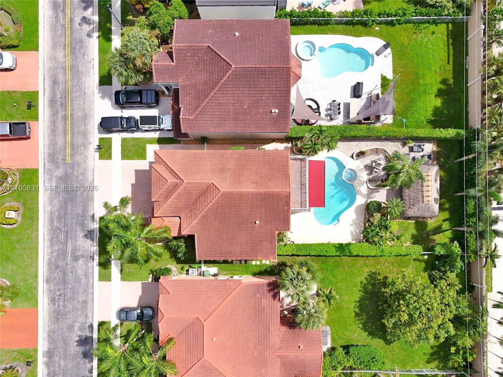 15612 SW 16th Court, Pembroke Pines, FL 33027 Aerial perspective of a residential property featuring an in-ground swimming pool with an integrated spa, a paved patio area, manicured landscaping, and a detached palapa