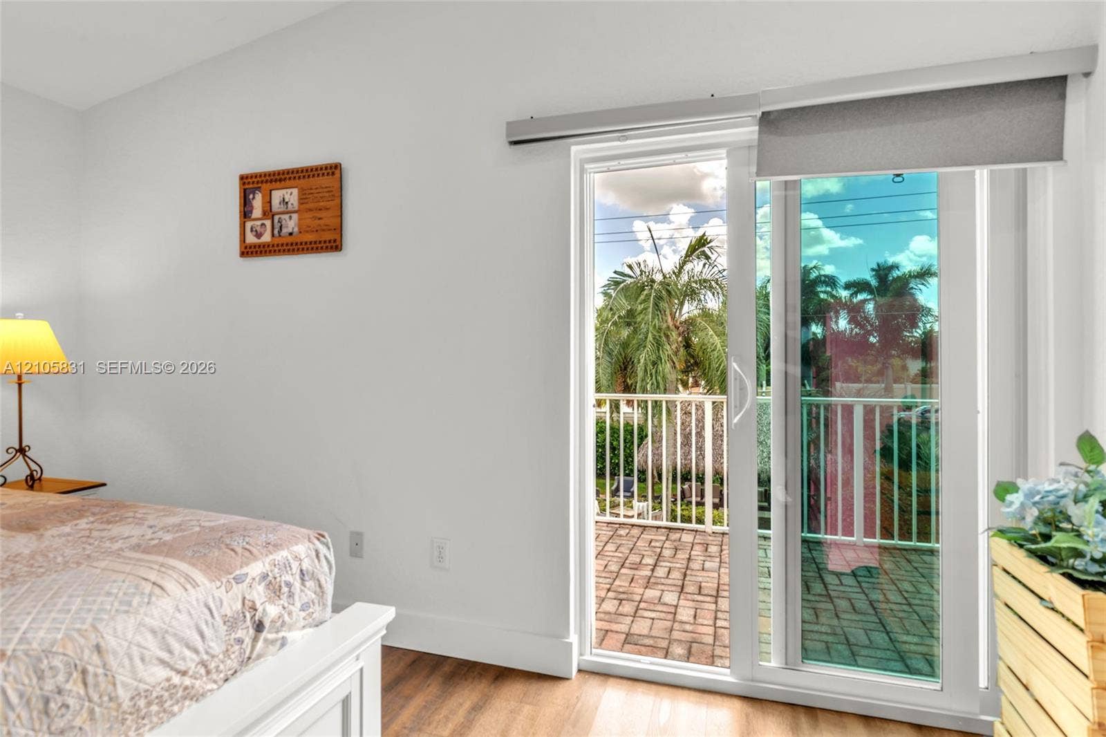 15612 SW 16th Court, Pembroke Pines, FL 33027 Sliding glass door with integrated roller shade, wood-finish flooring, and brick-paver balcony featuring a white metal railing