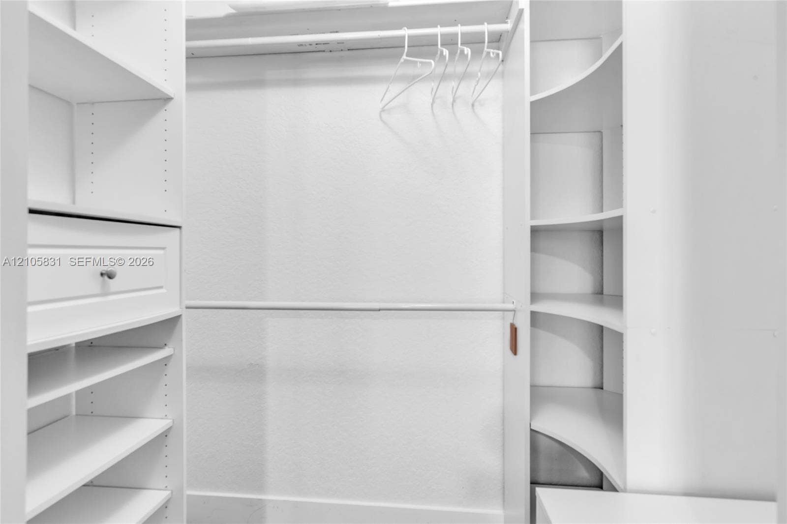 15612 SW 16th Court, Pembroke Pines, FL 33027 Walk-in closet featuring white custom built-in shelving, curved corner display units, dual-level hanging rods, and a soft-close drawer