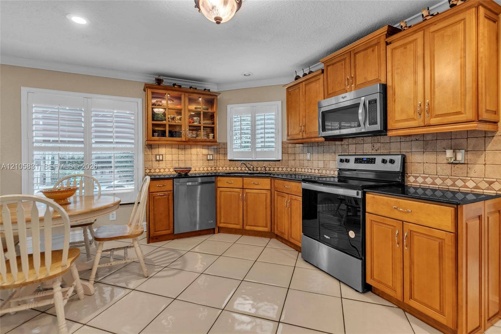 15612 SW 16th Court, Pembroke Pines, FL 33027 Kitchen featuring honey-toned wood cabinetry, stone-tiled backsplash, polished dark stone countertops, stainless steel appliances, and tile flooring