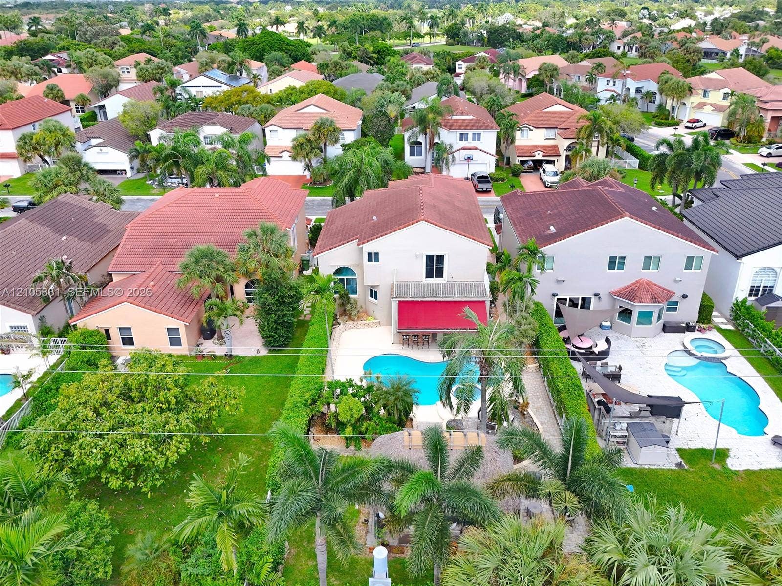 15612 SW 16th Court, Pembroke Pines, FL 33027 Aerial perspective of a two-story residence featuring a tile roof, an in-ground swimming pool, a concrete patio, and a privacy-hedged perimeter