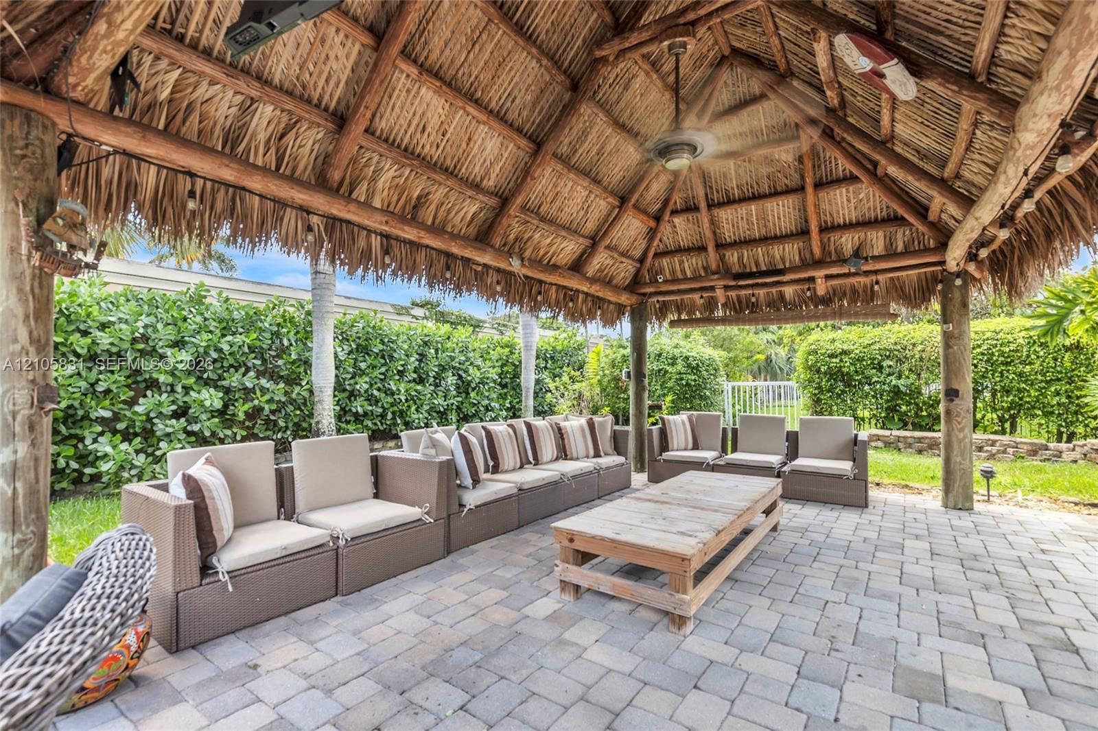 15612 SW 16th Court, Pembroke Pines, FL 33027 Covered tiki-style structure featuring a thatched roof, timber support beams, and a ceiling fan, set atop a paver patio