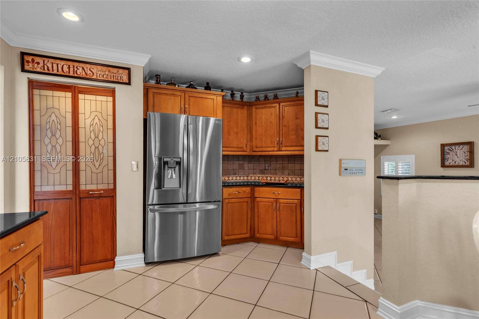 15612 SW 16th Court, Pembroke Pines, FL 33027 Kitchen featuring custom wood cabinetry, stainless steel French-door refrigerator, tile flooring, recessed lighting, and pantry doors with decorative glass inserts