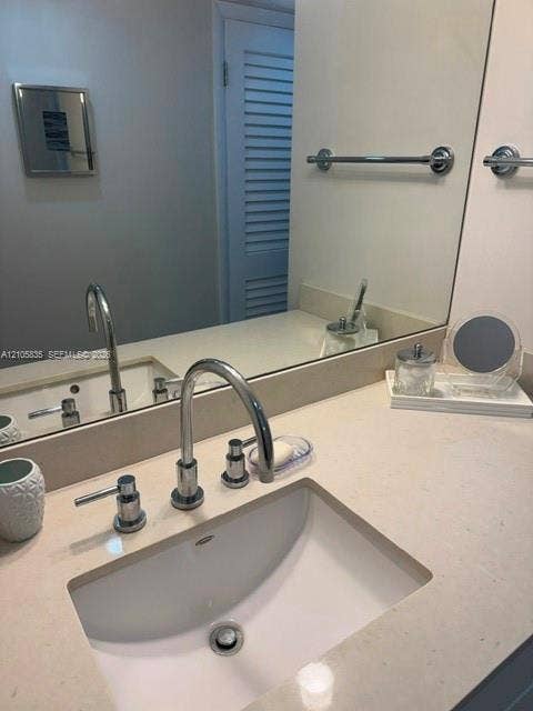 1400 S Ocean Drive, #1503, Hollywood, Hollywood, FL 33019 Bathroom vanity featuring a light-toned solid surface countertop, an integrated undermount sink, a chrome widespread faucet, and a large wall-mounted mirror