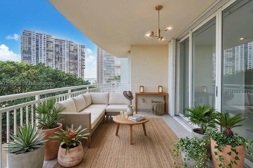 2475 Brickell Avenue, #704, Miami, FL 33129 Covered balcony featuring tile flooring, metal railing, and a multi-light brass chandelier